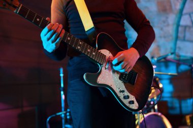 Sahnede elektro gitar çalan adam, yakın plan.