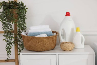 Beyaz dolapta havlu ve deterjan dolu çamaşır sepeti.