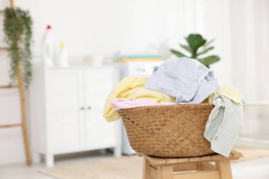 İçerideki ahşap masada giysileri olan çamaşır sepeti, metin için yer.