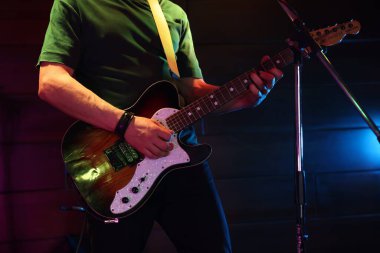 Sahnede elektro gitar çalan adam, yakın plan.