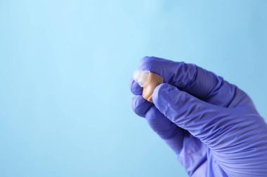 Açık mavi arka planda işitme cihazı olan doktor, yakın plan. Metin için boşluk