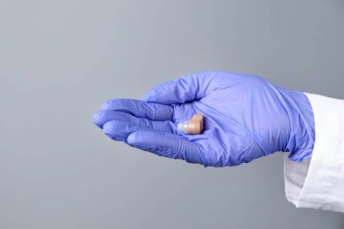 Açık gri arkaplanda işitme cihazı olan doktor, yakın plan.