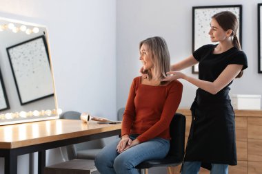 Kuaför, müşterisine kuaförde yeni saç kesimini gösteriyor. Metin için boşluk