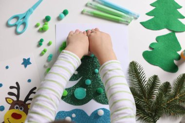 Küçük çocuk Noel kartpostalı hazırlıyor. Çocuk el yapımı.