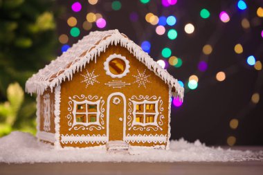 Masanın üzerinde bulanık ışıklara karşı güzel zencefilli kurabiye evi, mesaj için yeri olan yakın plan. Noel hediyesi