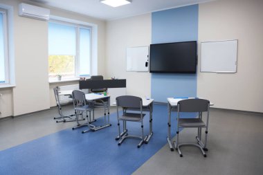 Okulda masaları, sandalyeleri ve televizyonu olan şık bir sınıf.