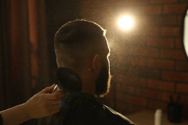 Kuaför, kuaförde adamın boynuna talk pudrası sürüyor.