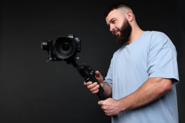 Siyah zemin üzerinde kamera olan titreşim dengeleyici kullanan kameraman, düşük açılı görünüm