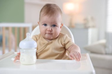 Evinde şezlongda yemek şişesi olan sevimli bir bebek.
