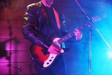 Sahnede elektro gitar çalan adam dumanlı, yakın plan