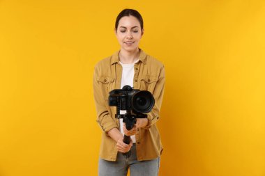 Sarı zemin üzerinde kamera olan titreşimli dengeleyici kullanan kameraman