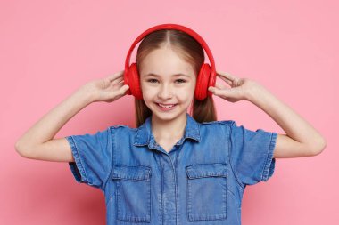 Pembe arka planda kulaklık takan tatlı bir kız.