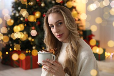 Odada Noel ağacının yanında bir fincan kakaolu güzel bir kadın var.