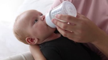Anne bebeğini şişeyle besliyor.