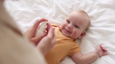 Anne evde bebeğinin yüzüne krem sürüyor, yakın plan.