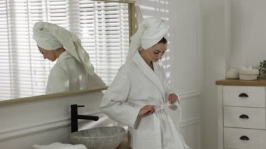 Güzel bir kadın bornozunu içeride bağlıyor.