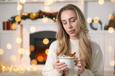Odasında şöminenin yanında kakaolu güzel bir kadın, Bokeh ışıkları. Noel sezonu