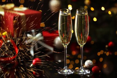 Yeni yıl kutlaması. Bir bardak köpüklü şarap, havai fişekler ve kartvizitte ışık.