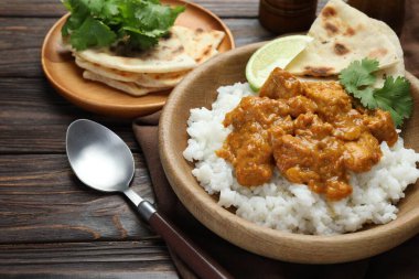 Pirinçli tavuk tikka masala, kişniş, kireç ve lavaş ahşap masada, yakın plan.