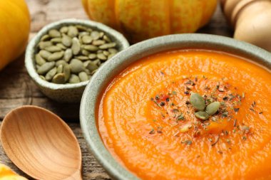 Lezzetli kabak kremalı çorba kasede tohumlar, sebze ve kaşık ahşap masada, yakın plan.