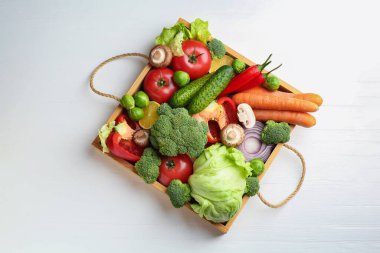 Beyaz ahşap masadaki sandıkta farklı taze taze sebzeler.