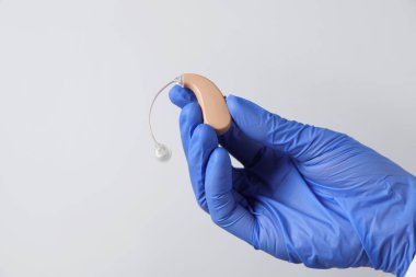 Açık gri arka planda işitme cihazı olan doktor, yakın plan. Metin için boşluk