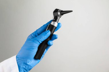 Açık gri arkaplanlı otoskoplu doktor, yakın plan. Metin için boşluk