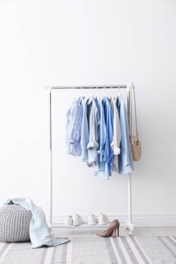 Askıda, çantada, ayakkabılarda ve beyaz duvarın yanında asılı farklı şık kıyafetler.