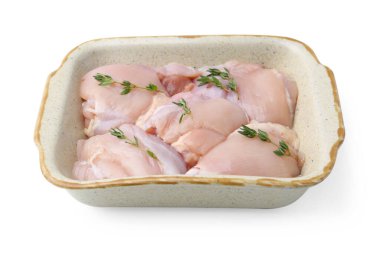 Çiğ tavuk butları ve kekik beyaz tencereye izole edilmiş pişirme kabında.