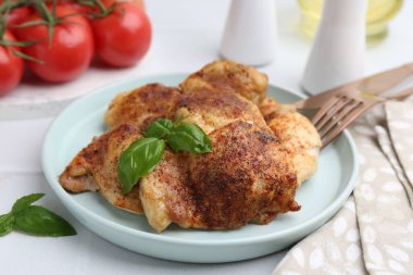 Lezzetli kızarmış tavuk butları ve fesleğenli beyaz fayanslı masa, yakın çekim.