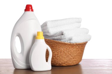 Temiz havlular ve ahşap masada beyaz arka planda deterjan bulunan çamaşır sepeti.