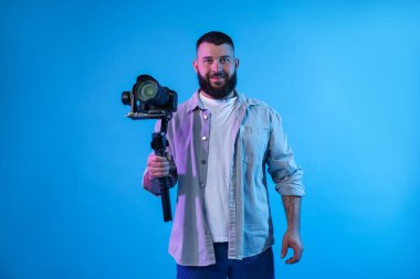 Açık mavi arkaplanda kameralı titreşim dengeleyici kullanan kameraman