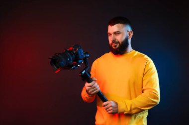 Kamerada çekim yapan kameraman, koyu arkaplandaki renk ışıklarına karşı titreşim dengeleyici kullanıyor. Metin için boşluk