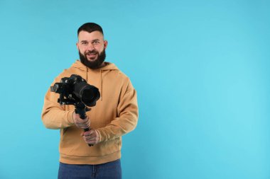 Kameraman açık mavi arkaplanda kameralı titreşimli dengeleyici kullanıyor. Metin için boşluk