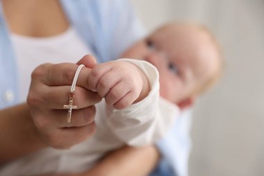 Vaftiz ayini. Kadın kucağında küçük bebek ve altın haç, seçici odaklanma