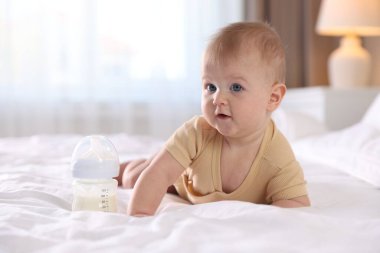 Evde yatağında biberonla beslenen tatlı bir bebek. Metin için boşluk