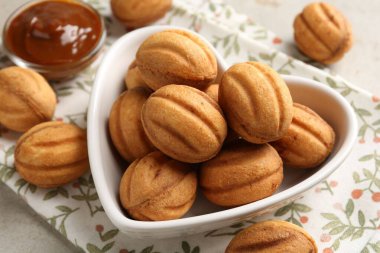 Lezzetli fındık şekilli kurabiyeler. Kaynatılmış konsantre süt, ışık masasında. Yakın plan.