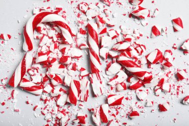 Gri arka planda ezilmiş baston şekerler, düz yatış. Noel hediyesi