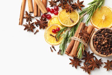 Farklı baharatlar, kuru portakal dilimleri, kızılcık ve taze biberiye beyaz ahşap masa üzerinde sıcak şarap, düz yatak. Metin için boşluk