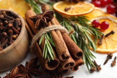 Farklı baharatlar, kuru portakal dilimleri, kızılcık ve taze biberiye ışık masasında sıcak şarap, yakın plan