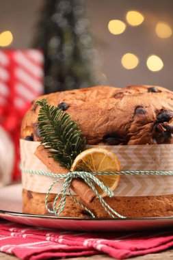 Baharatlı ve köknar dallı leziz bir Noel panettone pastası. Arka planda gri ışıklar ve yakın plan. Bokeh etkisi