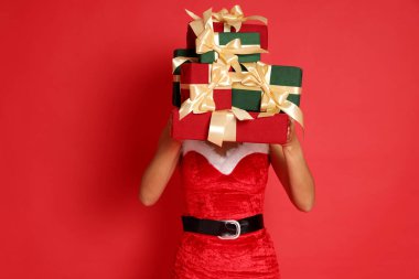 Kırmızı arka planda Noel hediyeleri olan Noel Anne kostümlü güzel bir kadın.