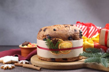 Baharatlı panettone keki, şekerli meyveler ve kahverengi masa üzerindeki Noel süsü, yakın plan.