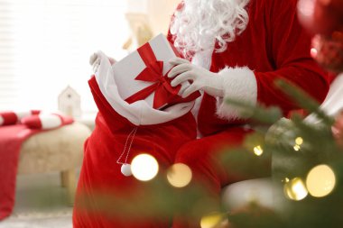 Noel Baba Noel ağacının yakınındaki çuvaldan hediyesini alıyor.