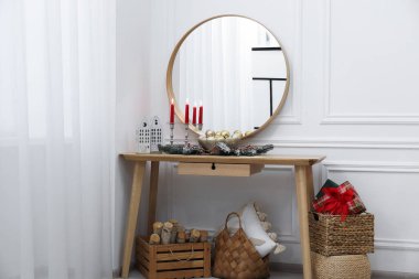 Ayna, Noel dekoru konsol masasında ve beyaz duvarın yanında yakacak odun. İç tasarım