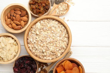 Tahıl yapıyorum. Yulaf gevrekleri, kurutulmuş meyveler ve beyaz ahşap masa üzerindeki diğer malzemeler. Metin için boşluk