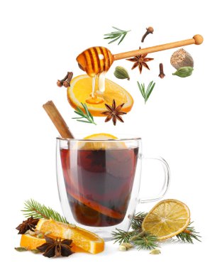 Sıcak şarap malzemeleri beyaz arka planda cam bardak sıcak içeceğe dökülüyor.