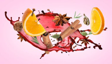 Mulled wine splash, spices and orange slices on pink background