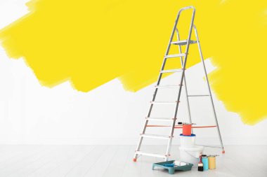 Dekoratörün eşyaları odada. Duvar kısmen sarı renge boyanmış. İç yenileme