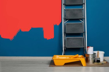 Dekoratörün eşyaları odada. Duvarın bir kısmı kırmızıya boyanmış. İç yenileme